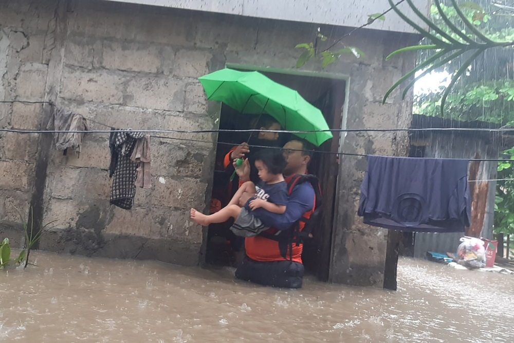 This handout photo taken on December 25, 2022 and received on December 26 from the Philippine Coast Guard shows rescuers evacuating a child from a flooded area in Ozamiz City, Misamis Occidental. Photo by Handout / Philippine Coast Guard (PCG) / AFP)