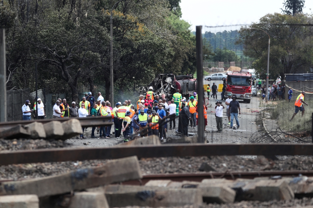 People gather near a burnt out truck at the entrance of the damaged bridge where a gas tanker exploded in Boksburg near Johannesburg, South Africa, on December 24, 2022. (REUTERS/Sumaya Hisham)