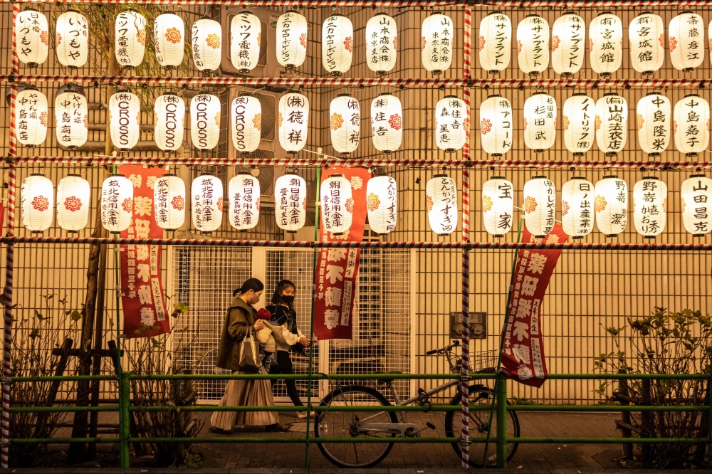 People walk past paper lanterns at a year-end fair in the Nihonbashi district of Tokyo on December 26, 2022. (Photo by Yuichi YAMAZAKI / AFP)