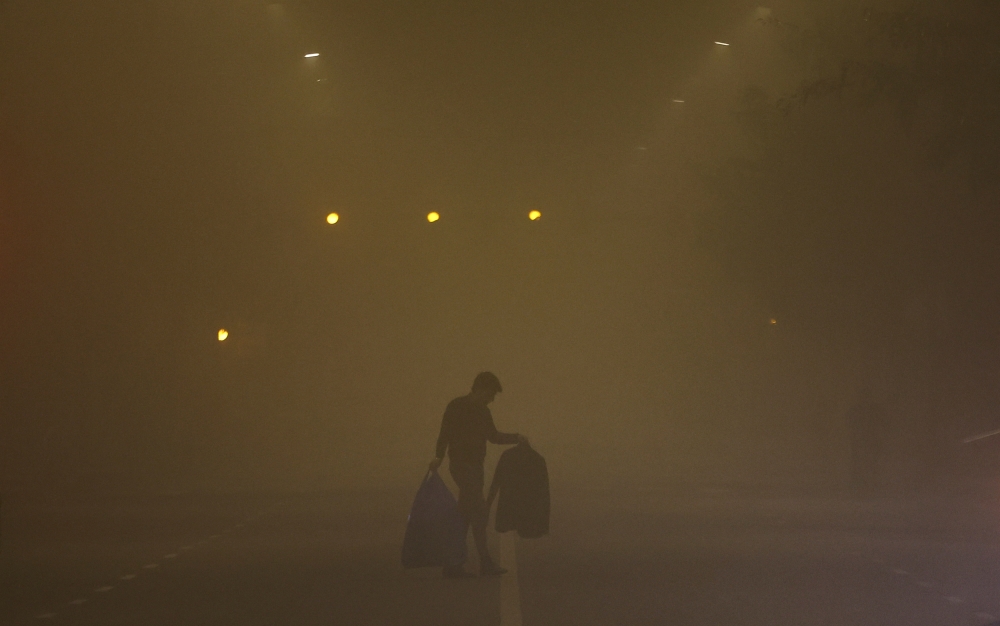 A man walks across a smoggy road on a cold winter morning in New Delhi, India, December 27, 2022. REUTERS/Anushree Fadnavis