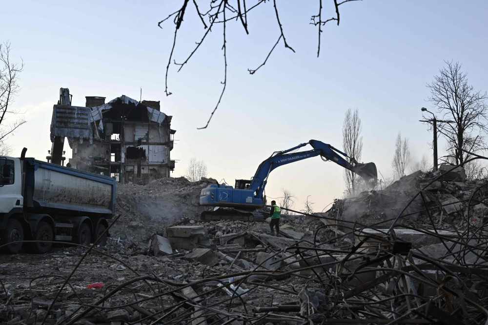 Workers dismantle a heavily damaged residential building in Irpin, northwest of Kyiv, on December 23, 2022, amid the Russian invasion of Ukraine. (Photo by Genya SAVILOV / AFP)