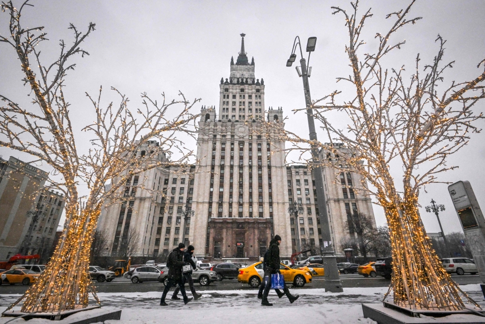 Pedestrians walk past Christmas and New Year decorations in front of the Red Gate Building Stalin-era skyscraper in Moscow, on December 28, 2022. (Photo by Yuri KADOBNOV / AFP)