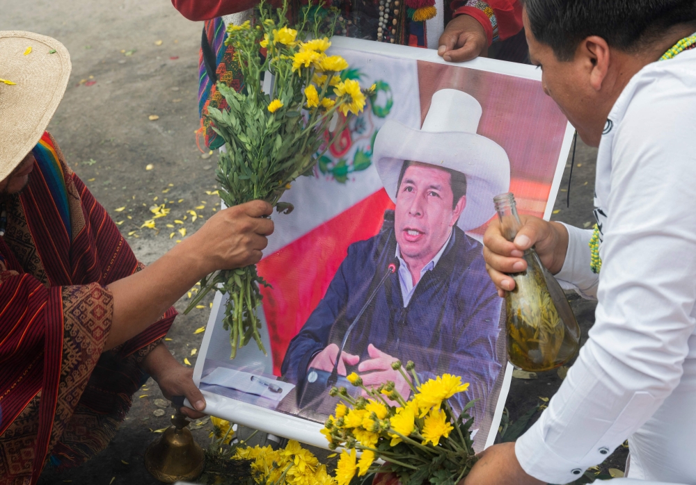 Peruvian shamans hold a poster of ousted Peruvian President Pedro Castillo while executing a ritual at the top of a hill over Lima to deliver their predictions for the coming year on December 28, 2022. (Photo by Cris Bouroncle  / AFP)