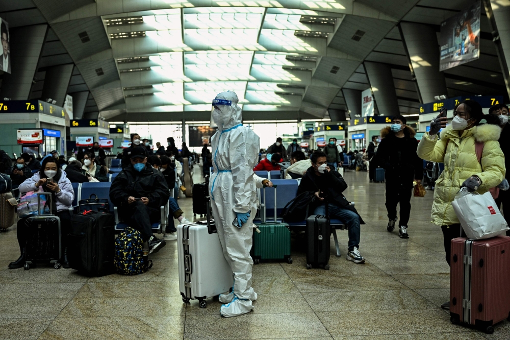 A passenger wearing protective gear is seen at a train station in Beijing on December 28, 2022. (Photo by Noel Celis / AFP)
