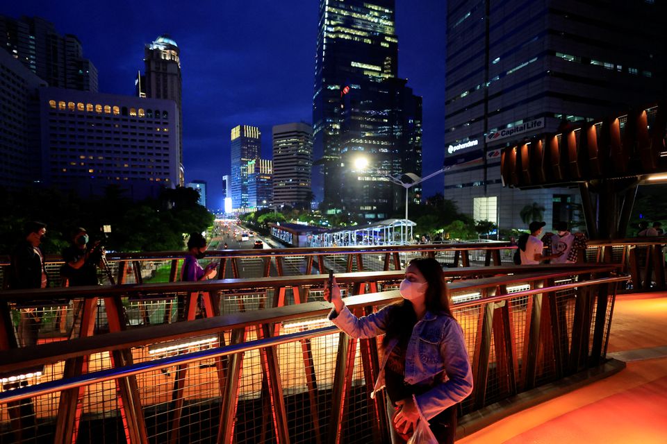 People wearing protective masks enjoy a pedestrian bridge during the dusk amid of the coronavirus disease (COVID-19) pandemic in Jakarta, Indonesia, March 15, 2022. REUTERS/Willy Kurniawan