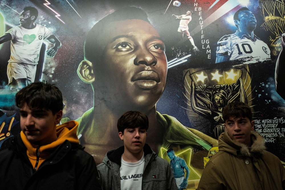 People pose in front of a mural of Brazilian soccer legend Pele while people mourn his death in Times Square in the Manhattan borough of New York City, U.S., December 29, 2022. REUTERS/Eduardo Munoz