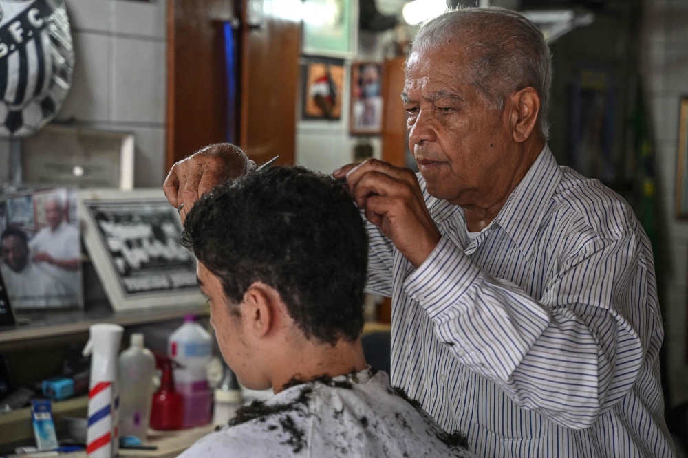 Barber Joao Araujo, known as Didi, who cut Brazilian football legend Pele's hair, works in his hairdressing salon in Santos, Brazil, on December 30, 2022.  (Photo by Nelson ALMEIDA / AFP)