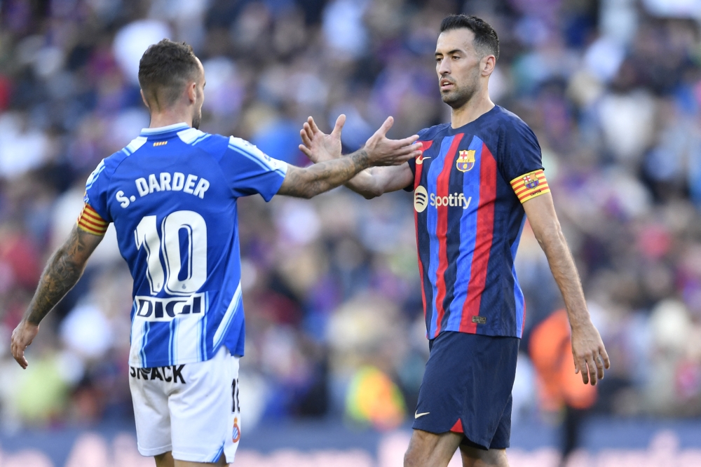 Espanyol's Spanish midfielder Sergi Darder (left) shakes hands with Barcelona's Spanish midfielder Sergio Busquets at the end of the Spanish League football match between FC Barcelona and RCD Espanyol at the Camp Nou stadium in Barcelona on December 31, 2022. (Photo by Pau BARRENA / AFP)