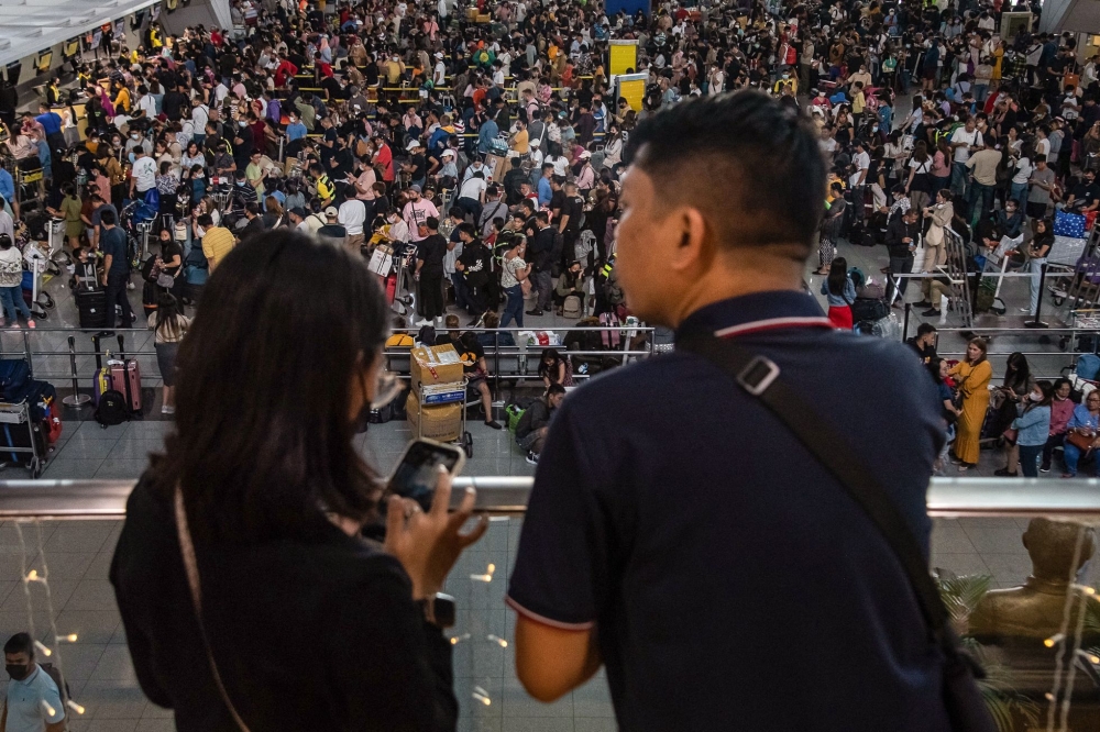 Passengers wait for information about their flights at terminal 3 of Ninoy International Airport in Pasay, Metro Manila on January 1, 2023. (Photo by KEVIN TRISTAN ESPIRITU / AFP)