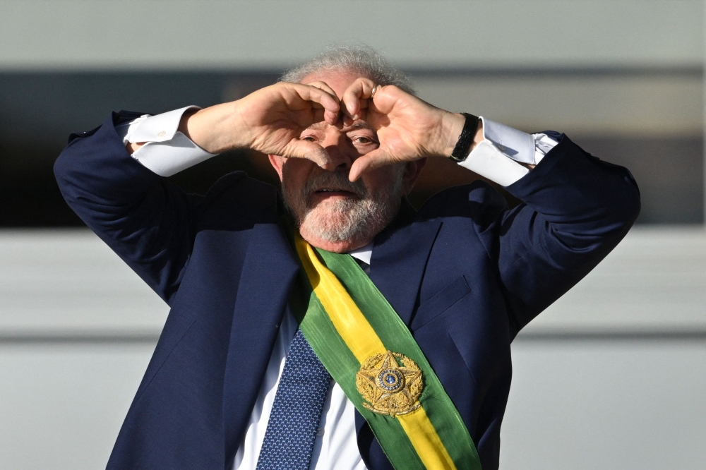 Brazil's new President Luiz Inacio Lula da Silva gestures at supporters making a heart sign with his hands at Planalto Palace after their inauguration ceremony at the National Congress, in Brasilia, on January 1, 2023. (Photo by Evaristo SA / AFP)
