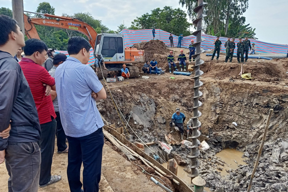 Rescuers look down into the site of where a 10-year-old boy is thought to be trapped in a 35-metre deep shaft at a bridge construction area in Vietnam's Dong Thap province on January 2, 2023. Photo by AFP