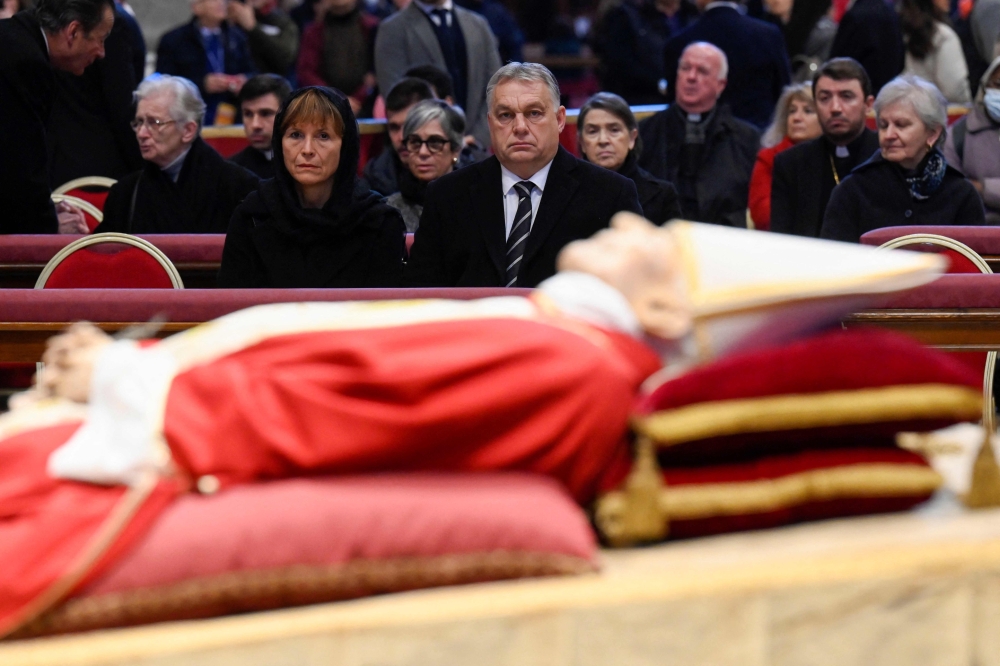 This handout picture taken and released on January 3, 2023 shows Hungarian Prime Minister Viktor Orban (second left) and his wife Aniko Levai paying their respect to Pope Emeritus Benedict XVI as his body lays in state at St. Peter's Basilica in the Vatican.  (Photo by Handout / VATICAN MEDIA / AFP)