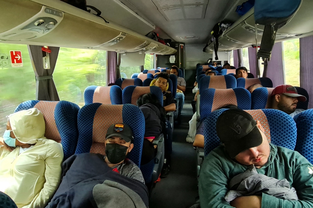 Migrants sleep on a bus during their journey from the Nicaraguan border to Guatemala in Choluteca, Honduras, on November 23, 2022. (Photo by Stringer / AFP)