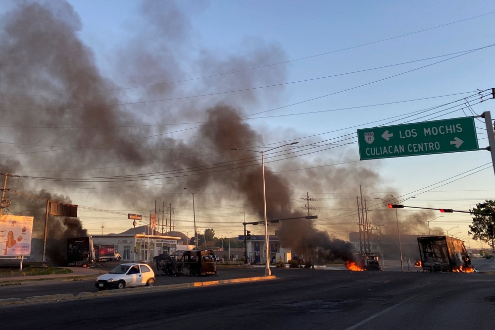 Burning vehicles are seen crossed in the street during an operation to arrest the son of Joaquin 'El Chapo' Guzman, Ovidio Guzman, in Culiacan, Sinaloa state, Mexico, on January 5, 2023. (Photo by Marcos Vizcarra / AFP)