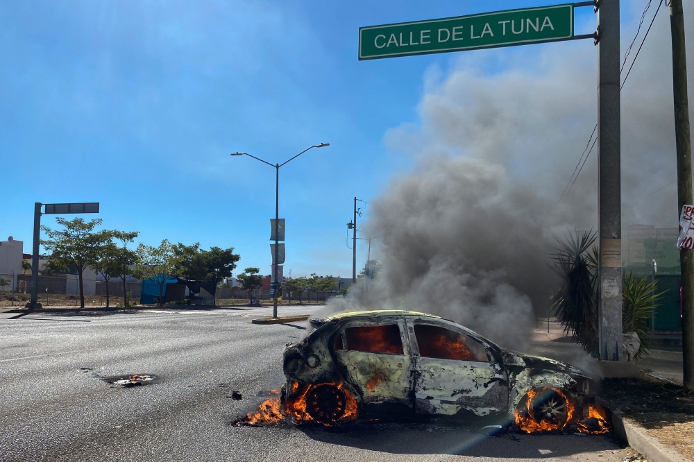 A burning car is seen on the street during an operation to arrest the son of Joaquin 'El Chapo' Guzman, Ovidio Guzman, in Culiacan, Sinaloa state, Mexico, on January 5, 2023. (Photo by Juan Carlos Cruz / AFP)