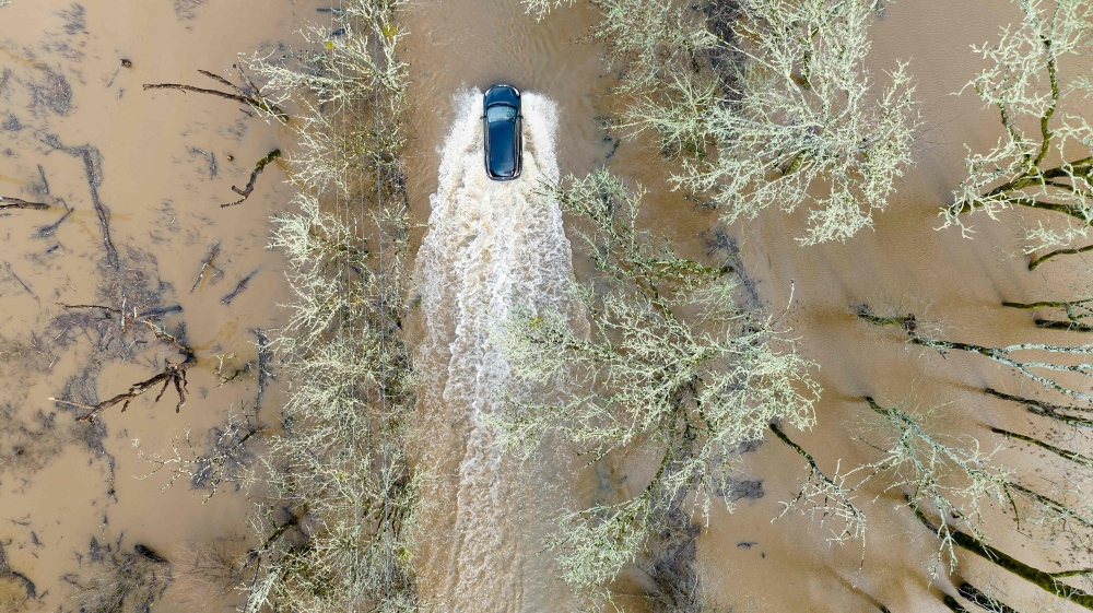 A vehicle drives on a flooded road in Sebastopol, California, on January 5, 2023. (Photo by JOSH EDELSON / AFP)