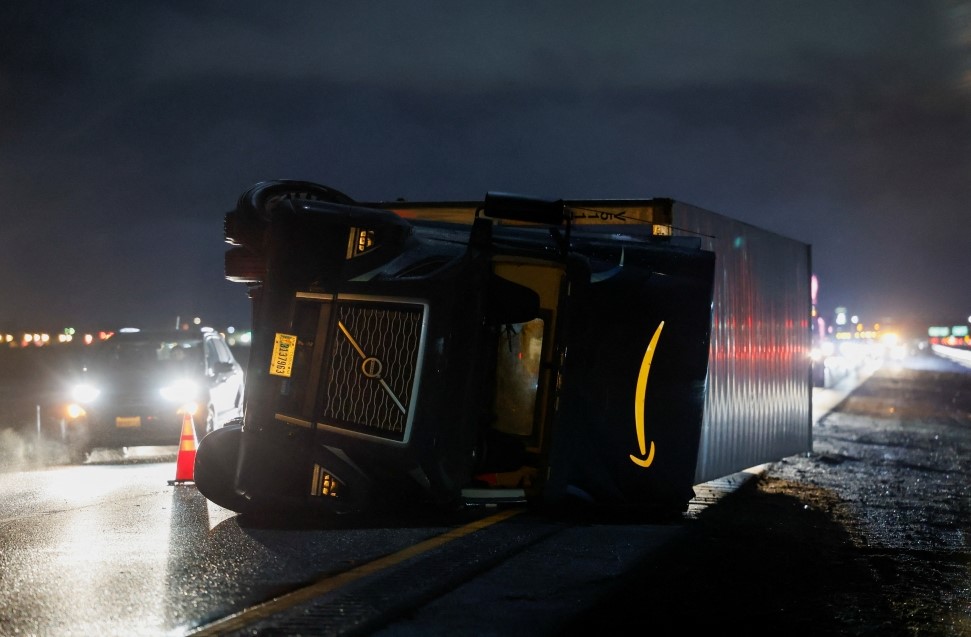 A semi tractor-trailer lies on its side along after it was toppled by high winds during a winter storm along Interstate 5 in Woodland, California, US, January 8, 2023. (REUTERS/Fred Greaves)