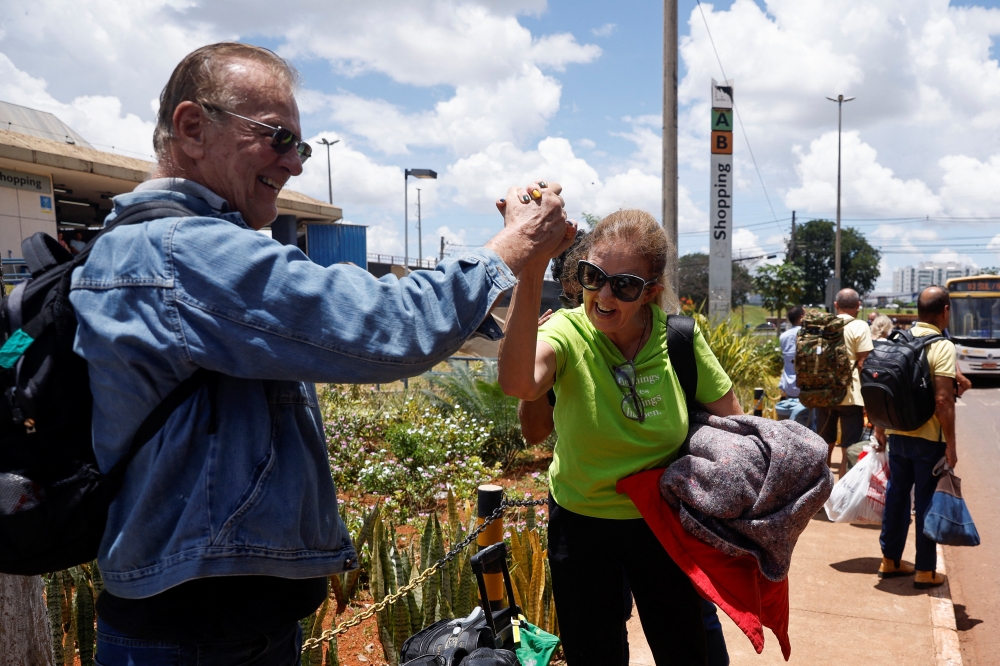 Supporters of Brazil's former President Jair Bolsonaro who were detained stand outside as they leave a bus after a camp set by supporters was dismounted in front of the Army Headquarters, in Brasilia, Brazil, on January 10, 2023. REUTERS/Amanda Perobelli