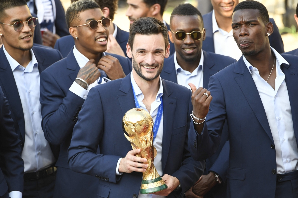 In this file photo taken on July 16, 2018 France's goalkeeper Hugo Lloris smiles and holds the trophy next to France's midfielder Paul Pogba (right) as they arrive for a reception at the Elysee Presidential Palace in Paris after French players won the Russia 2018 World Cup final football match.  (Photo by Lionel BONAVENTURE / AFP)