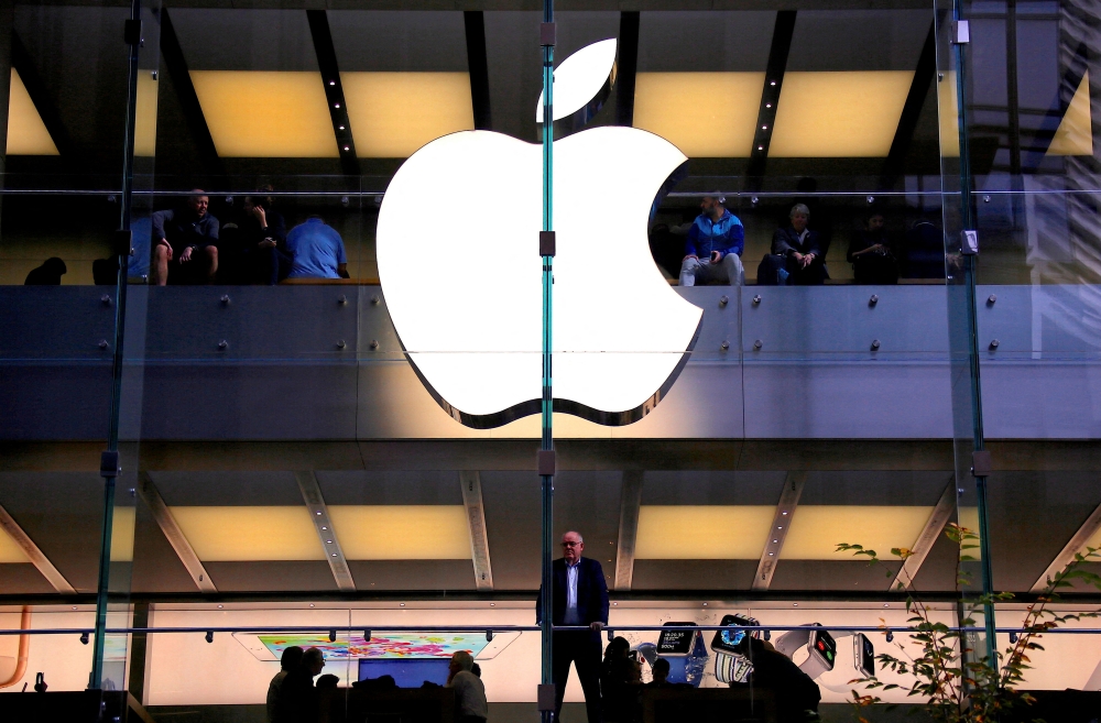  A customer stands underneath an illuminated Apple logo as he looks out the window of the Apple store located in central Sydney, Australia, on May 28, 2018. File Photo / Reuters