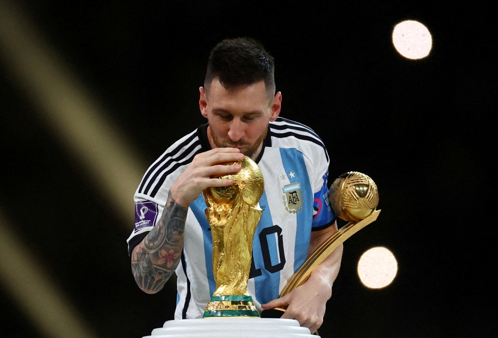 Argentina's Lionel Messi kisses the World Cup trophy after receiving the Golden Ball award as he celebrates after winning the World Cup at the Lusail Stadium in Qatar on December 18, 2022. (REUTERS/Kai Pfaffenbach)