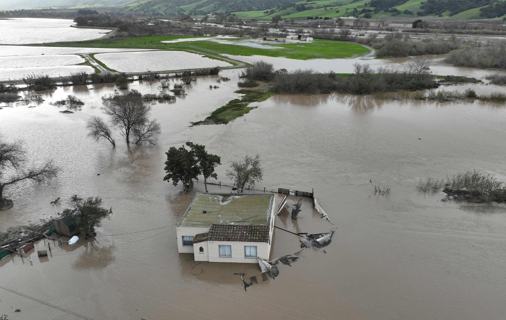 In an aerial view, a home is seen submerged in floodwater as the Salinas River begins to overflow its banks on January 13, 2023 in Salinas, California. Several atmospheric river events continue to pound California with record rainfall and high winds. Justin Sullivan/Getty Images/AFP