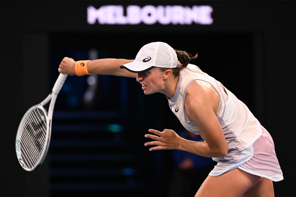Poland's Iga Swiatek hits a return against Germany's Jule Niemeier during their women's singles match on day one of the Australian Open tennis tournament in Melbourne on January 16, 2023. (Photo by WILLIAM WEST / AFP) 