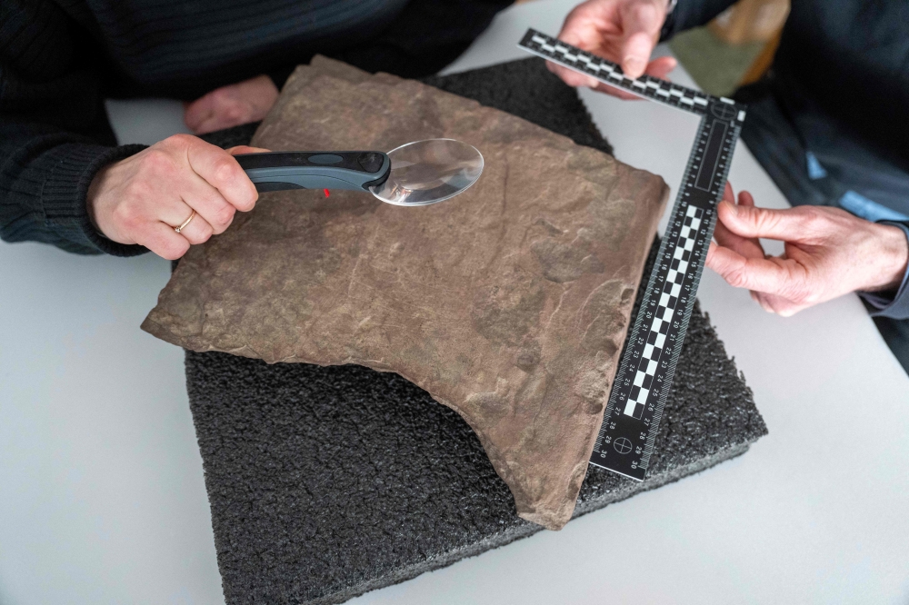 An archaeologist inspects on January 17, 2032, in Oslo a sandstone rock, believed to be the world's oldest runestone inscribed almost 2,000 years ago. (Photo by Javad Parsa / NTB / AFP