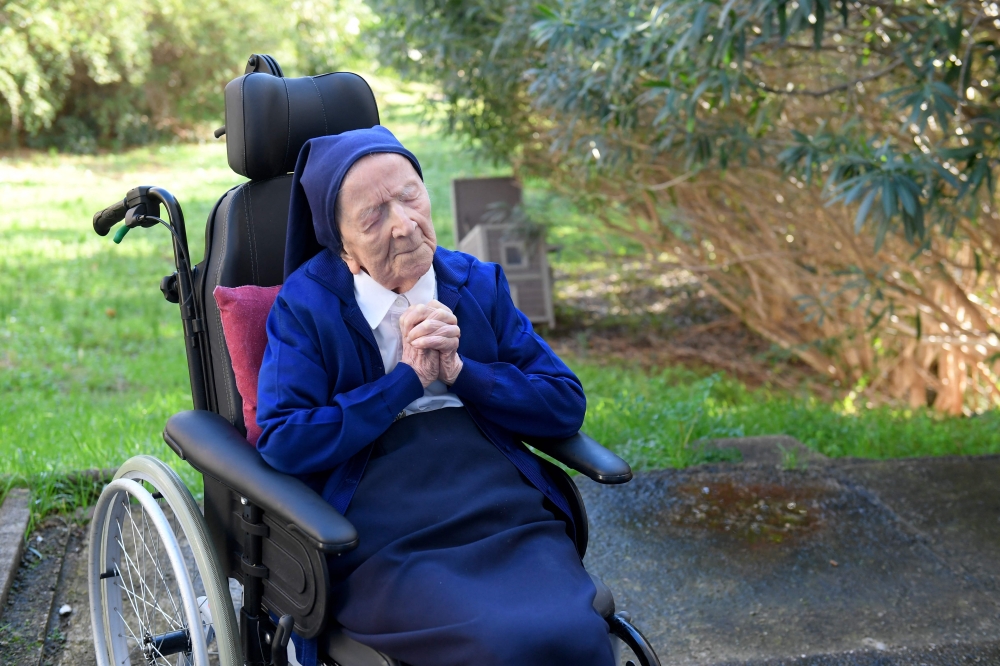 In this file photo taken on February 10, 2021 Sister Andre, Lucile Randon in the registry of birth, prays in a wheelchair, on the eve of her 117th birthday, in an EHPAD (Housing Establishment for Dependant Elderly People) in Toulon, southern France, where she has been living since 2009. (Photo by Nicolas Tucat / AFP)