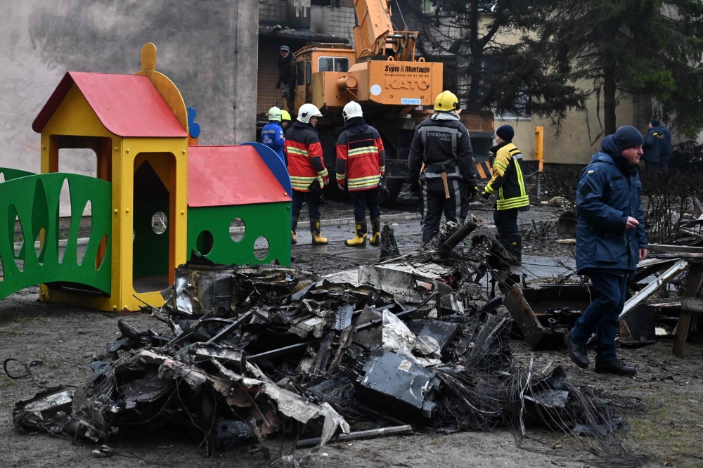 Firefighters work near the site where a helicopter crashed near a kindergarten in Brovary, outside the capital Kyiv, killing Sixteen people, including two children and Ukrainian interior minister, on January 18, 2023, amid the Russian invasion of Ukraine. (Photo by Sergei Supinsky / AFP)