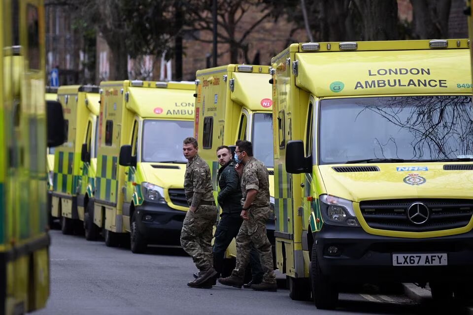 Military personnel and an ambulance worker walk between parked ambulances outside their Waterloo station, amid a strike by ambulance workers due to a dispute with the government over pay, in London, Britain on January 11, 2023. REUTERS/Toby Melville/File Photo
