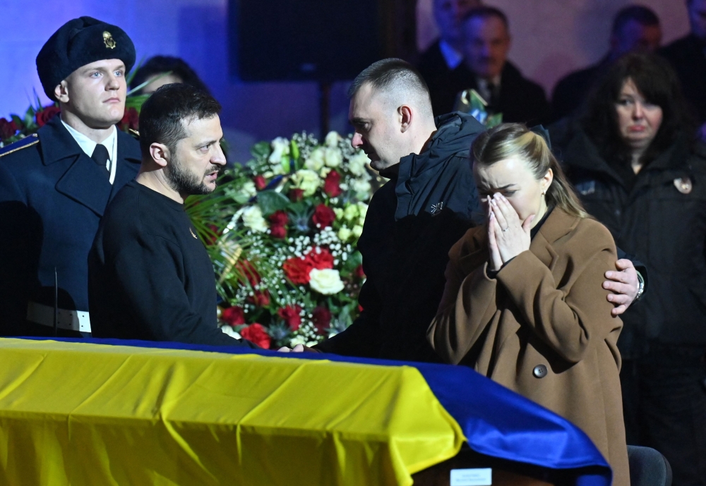 Ukrainian President Volodymyr Zelenskyy offers relatives his condolences during the funeral ceremony of Ukrainian Interior Minister Denys Monastyrsky and other employees of his department at the Ukrainian House in Kyiv on January 21, 2023. (Photo by Sergei SUPINSKY / AFP)