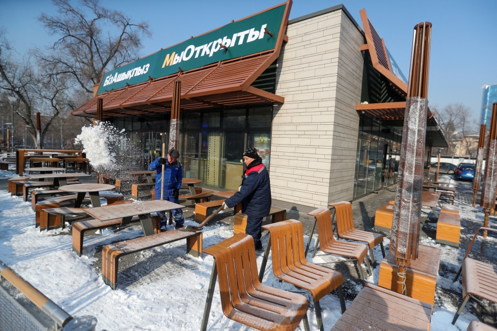 Employees remove snow outside a fast food restaurant, which used to operate under the McDonald's brand and reopened with no branding weeks after the U.S. company left the local market, in Almaty, Kazakhstan January 23, 2023. A sign reads: 