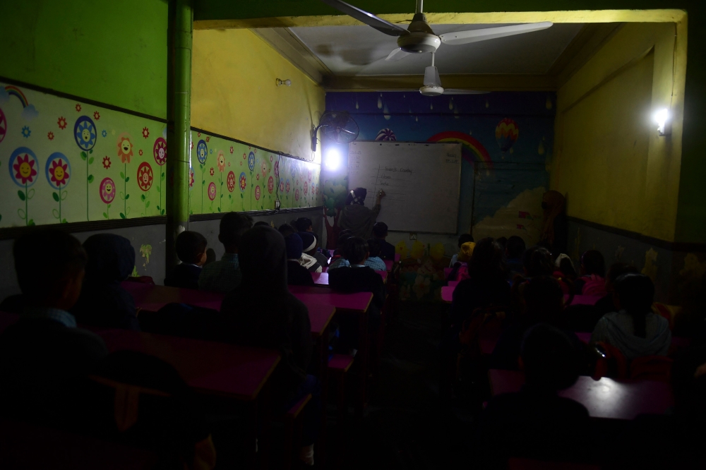Students attend a class at a private school during a nationwide power outage in Karachi on January 23, 2023. - A massive power breakdown in Pakistan on January 23 affected most of the country's more than 220 million people, including in the mega cities of Karachi and Lahore. (Photo by Asif HASSAN / AFP)
