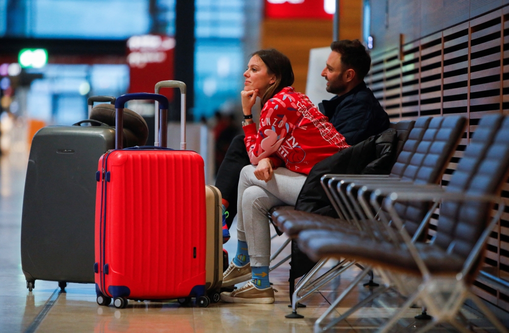 People wait with their luggages during a general strike by employees over pay demands, at the Berlin Brandenburg Airport (BER), in Schoenefeld near Berlin, Germany January 25, 2023. REUTERS/Michele Tantussi