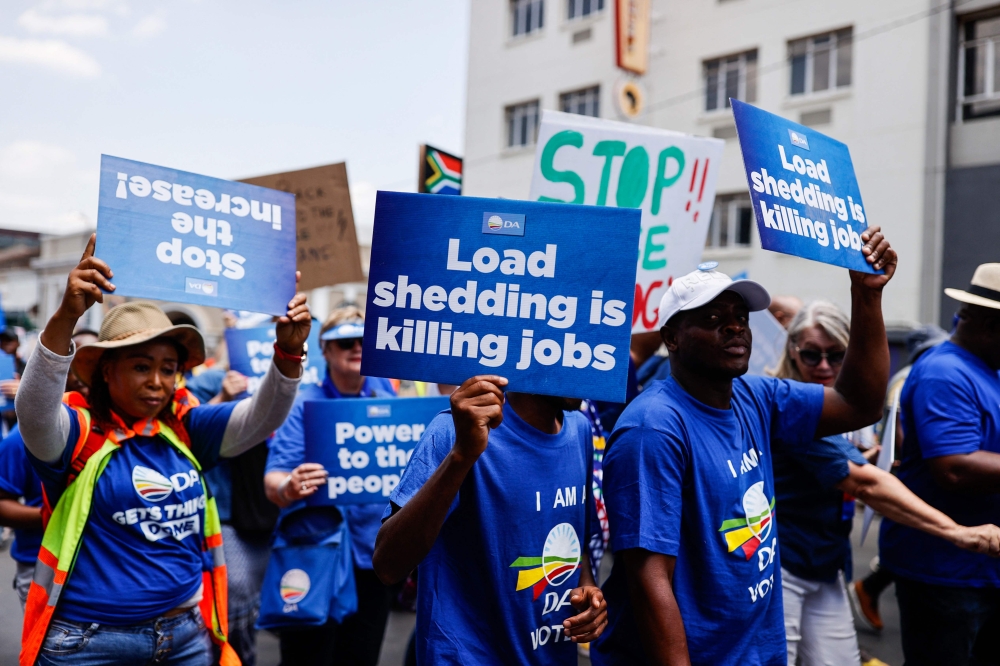Democratic Alliance (DA) members hold placards as they march to Luthuli House, the headquarters of the ruling african National Congress (ANC), during a protest against prolonged energy crisis that has seen South africans experience record power cuts, in Johannesburg on January 25, 2023. (Photo by PHILL MAGAKOE / AFP)
