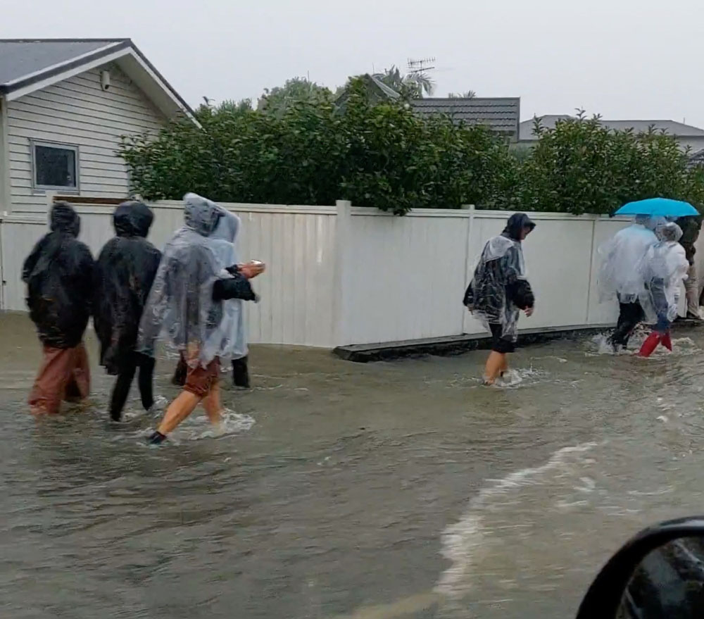 People walk on a flooded street after Elton John?s concert was canceled due to bad weather, in Auckland, New Zealand, January 27, 2023 in this screen grab obtained from a social media video. Duane Moyle/via REUTERS