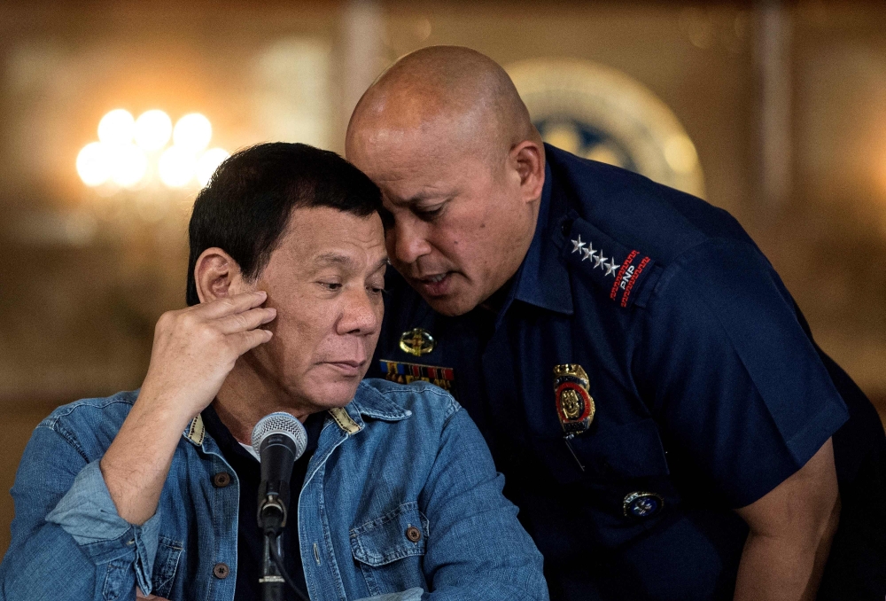 This file photo taken on January 30, 2017 shows then-Philippine President Rodrigo Duterte (left) talking to Philippine National Police director general Ronald Dela Rosa during a press conference at the Malacanang palace in Manila. (Photo by Noel Celis / AFP)
