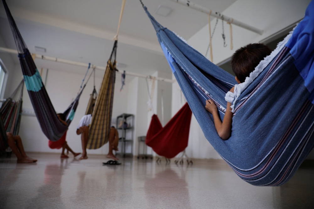 A Yanomami indigenous child, who is treated for malnutrition, sits in a hammock at a special yard for indigenous people of the Santo Antonio Children's Hospital, in Boa Vista, Roraima state, Brazil, January 27, 2023. (REUTERS/Amanda Perobelli)