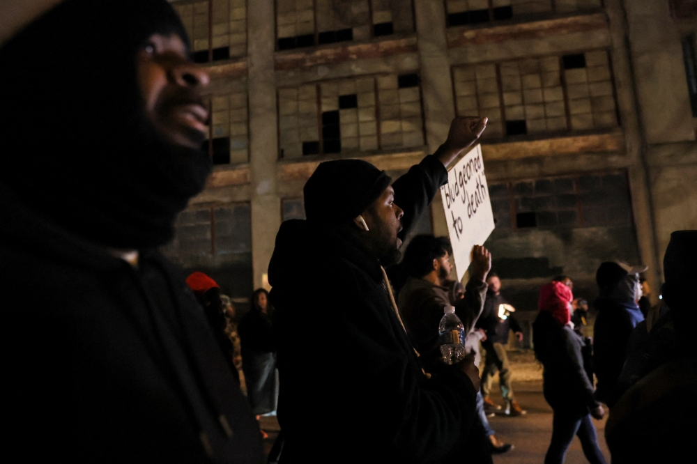 A demonstrator holds a placard as people march during a protest on the day of the release of a video showing police officers beating Tyre Nichols, the young Black man who died three days after he was pulled over while driving during a traffic stop by Memphis police officers, in downtown Memphis, Tennessee, U.S., January 27, 2023. REUTERS/Leah Millis

