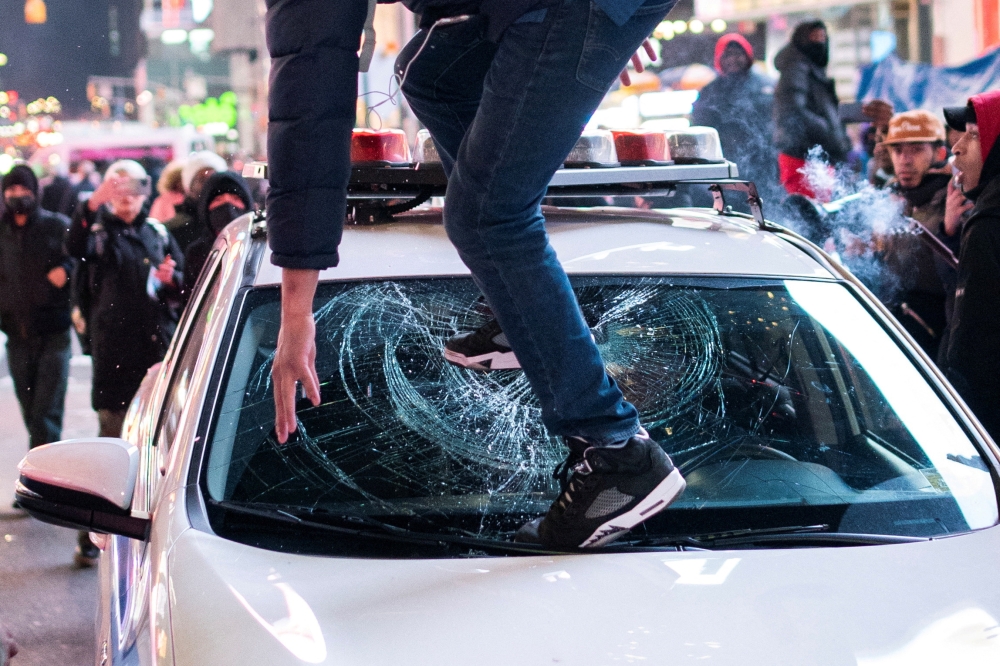A protestor steps on the windshield of a police vehicle, on the day of the release of a video showing police officers beating Tyre Nichols, the young Black man who died three days after he was pulled over while driving during a traffic stop by memphis police officers, in New York, U.S., January 27, 2023. REUTERS/Eduardo Munoz