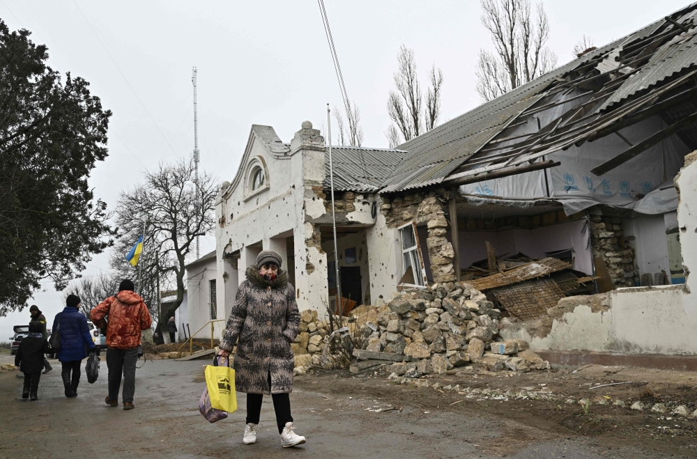 Local residents walk in front of a heavily damaged local administration building in the village of Lymany, Mykolaiv region on January 28, 2023, amid the Russian invasion of Ukraine. (Photo by Genya SAVILOV / AFP)