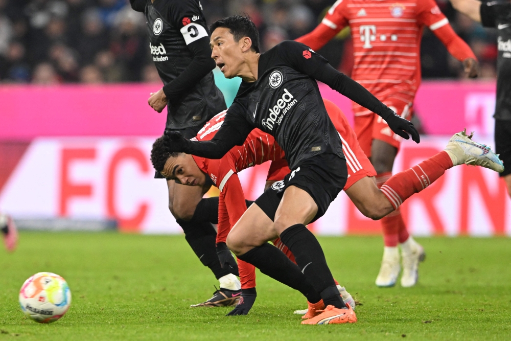 Frankfurt's Japanese midfielder Makoto Hasebe (front) and Bayern Munich's German midfielder Jamal Musiala vie for the ball during the German Bundesliga football match between Bayern Munich and Eintracht Frankfurt in Munich, southern Germany, on January 28, 2023.