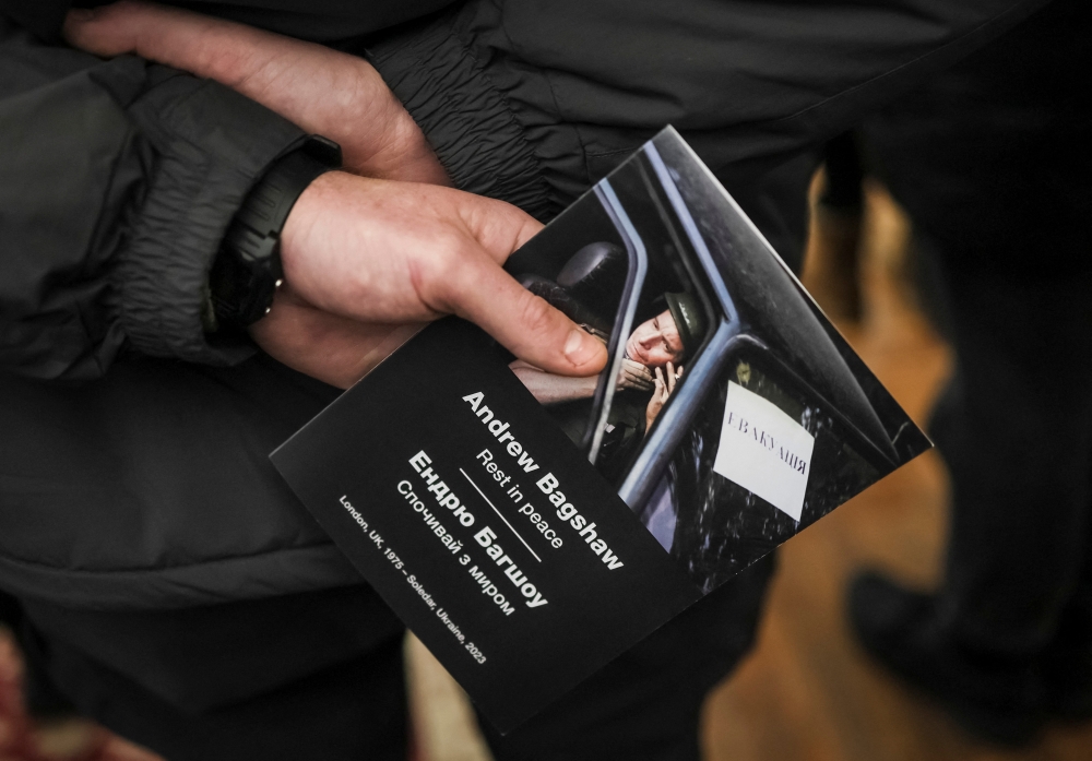 A volunteer holds a booklet with a portrait of Andrew Bagshaw, one of the two British volunteers killed in eastern Ukraine while attempting a rescue from Soledar, amid Russia's attack on Ukraine, during a memorial service in Kyiv, Ukraine, January 29, 2023. (REUTERS/Gleb Garanich)