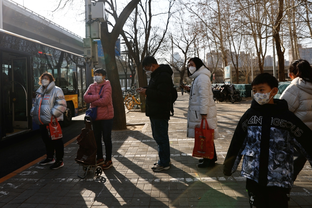 People wait at a bus stop in Beijing's Central Business District (CBD), during the morning rush hour following the Chinese Lunar New Year holiday, in Beijing, China January 30, 2023. REUTERS/Tingshu Wang