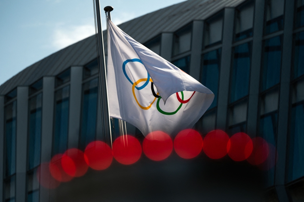 This file photo taken on March 8, 2021 shows the Olympic flag floating next to the headquarters of the International Olympic Committee in Lausanne. (Photo by Fabrice Coffrini / AFP)