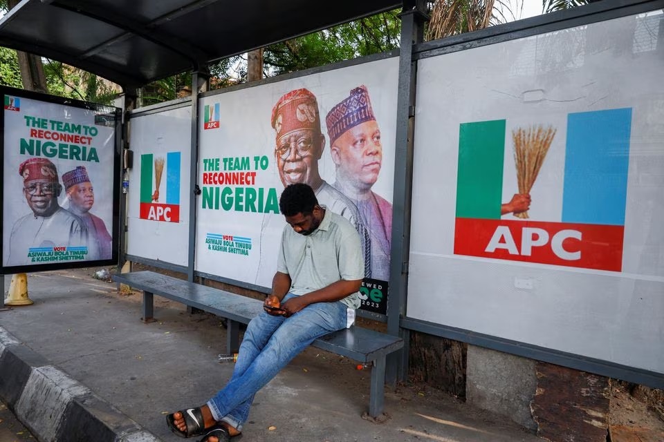 A man sits at a bus stop decorated with electoral campaign posters of All Progressives Congress (APC) Presidential candidate, Bola Tinubu, with his running mate Kashim Shettima, ahead of Nigeria's Presidential election, in Lagos, Nigeria January 31, 2023. REUTERS/Temilade Adelaja