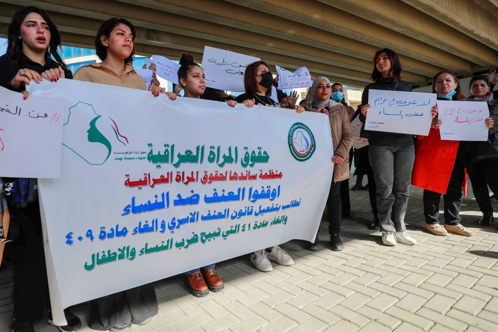 Iraqi women's rights activists lift placards during a rally near the Supreme Judicial Council in Baghdad on February 5, 2023, to protest the killing of Iraqi youtuber Tiba al-Ali by her father in Diwaniyah. (Photo by AHMAD AL-RUBAYE / AFP)