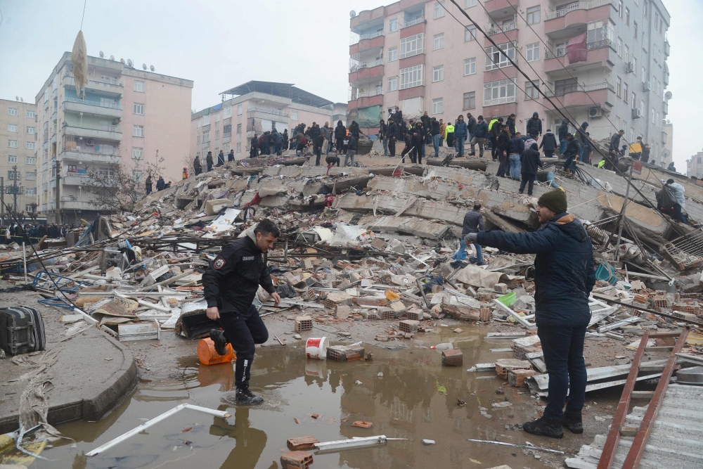 People search for survivors through the rubble in Diyarbakir, on February 6, 2023, after a 7.8-magnitude earthquake struck the country's south-east. - At least 284 people died in Turkey and more than 2,300 people were injured in one of Turkey's biggest quakes in at least a century, as search and rescue work continue in several major cities. (Photo by ILYAS AKENGIN / AFP)