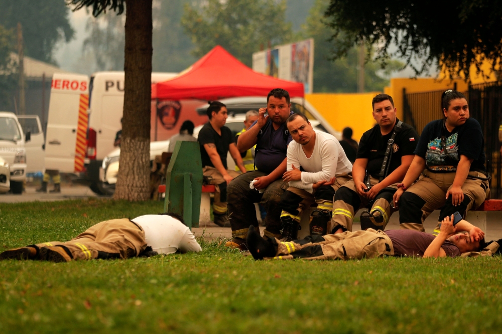 Firefighters rest at the command post after fighting forest fires in Santa Juana, Concepcion province, Chile on February 6, 2023.  (Photo by JAVIER TORRES / AFP)